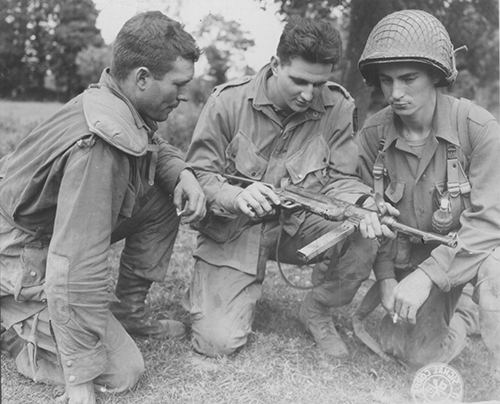 3 American paratroopers study a german machine pistol