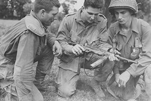 3 American paratroopers study a german machine pistol