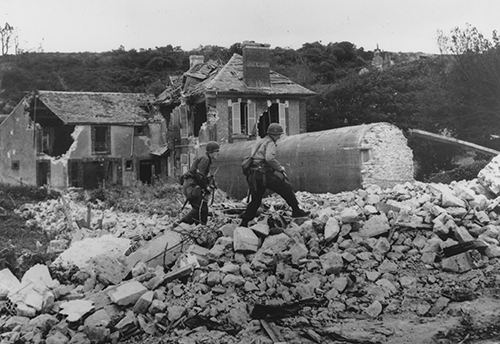 American soldiers pick their way across the rubble