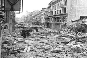 A patrol struggles along a rubble choked street