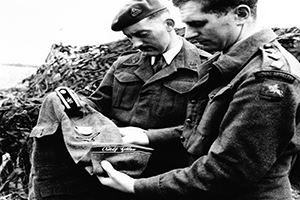 Officers examining the tunic of a corporal in the Adolf Hitler unit
