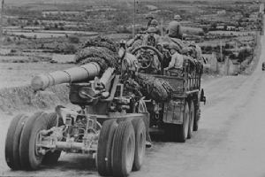 Mack artilery trailer towing a 155mm gun.