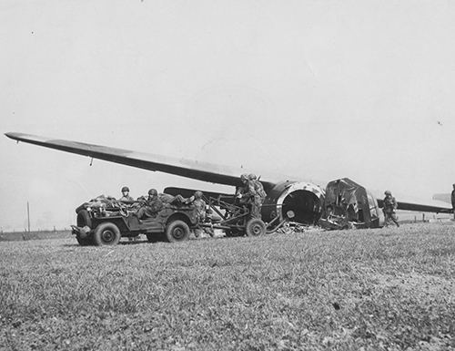 Airborne troops drive a jeep out of a crashed Horsa
