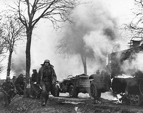 Enemy troops pass burning US vehicles