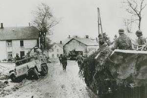 Waffen-SS Panzergrenadiers move past wrecked American truck